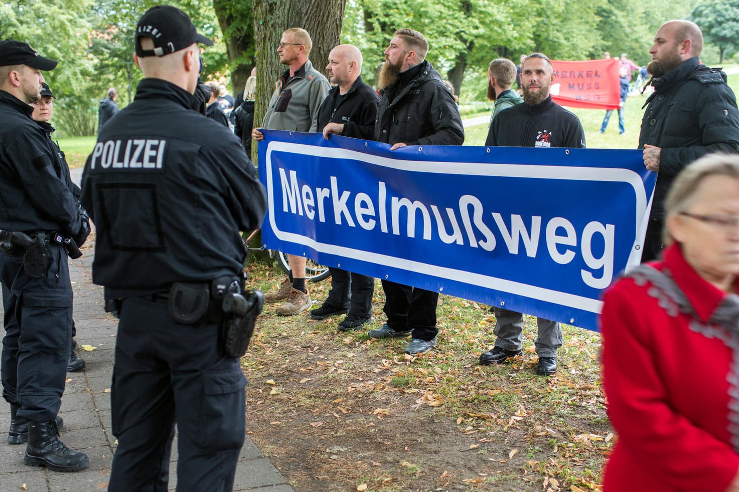 Merkel-Gegner stehen mit Transparenten am Rand der CDU-Wahlkampfveranstaltung in Strasburg.
