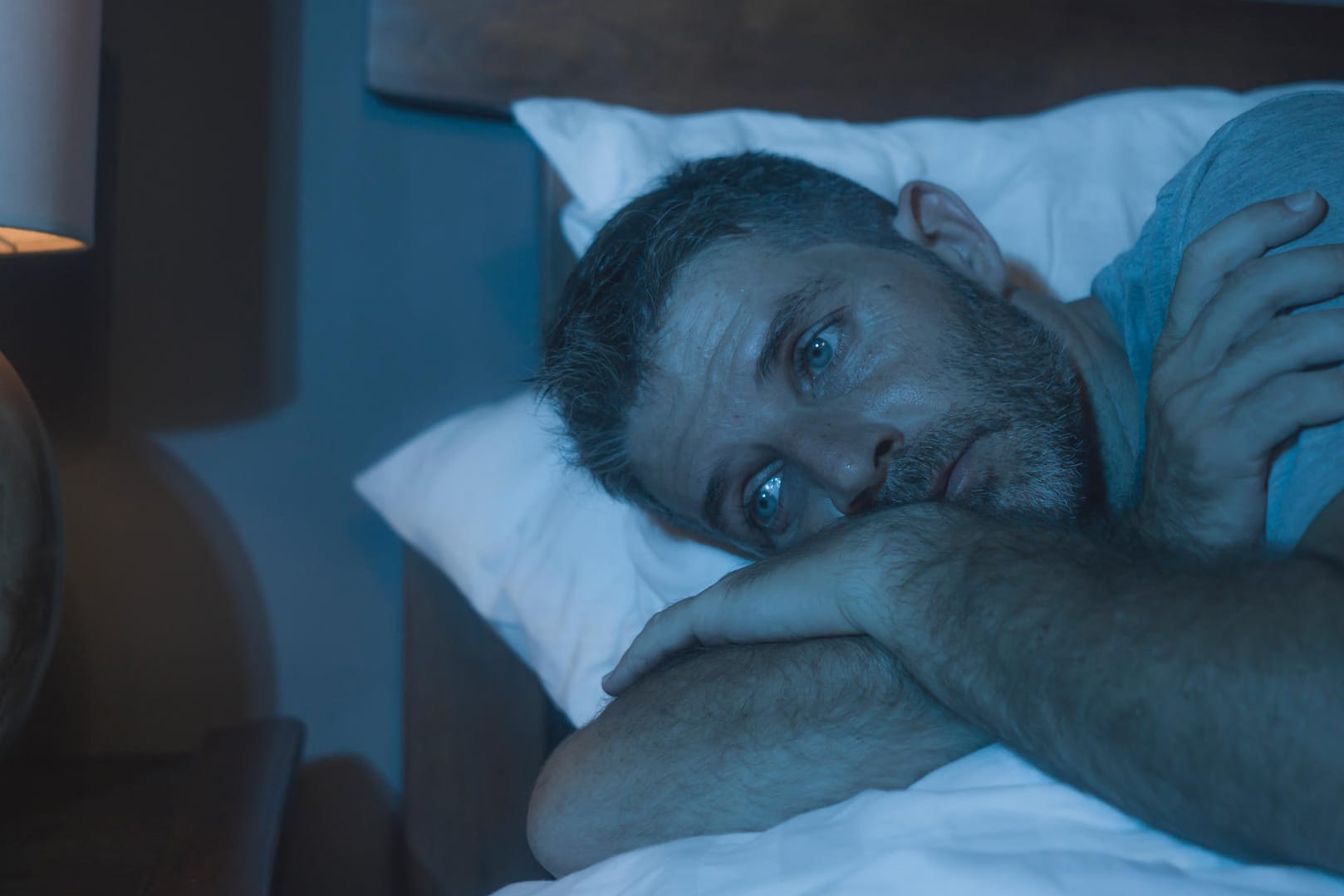 Mann liegt schlaflos im Bett: Schlafstörungen können im Alltag stark belasten. Mann liegt schlaflos im Bett: Schlafstörungen können im Alltag stark belasten.