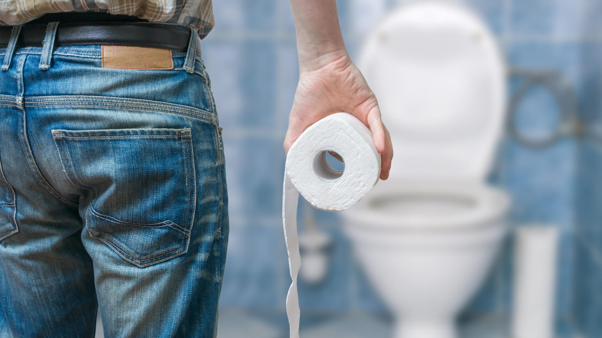Ein Mann steht vor der Kloschüssel und hält Klopapier in der Hand. Ein Mann steht vor der Kloschüssel und hält Klopapier in der Hand.