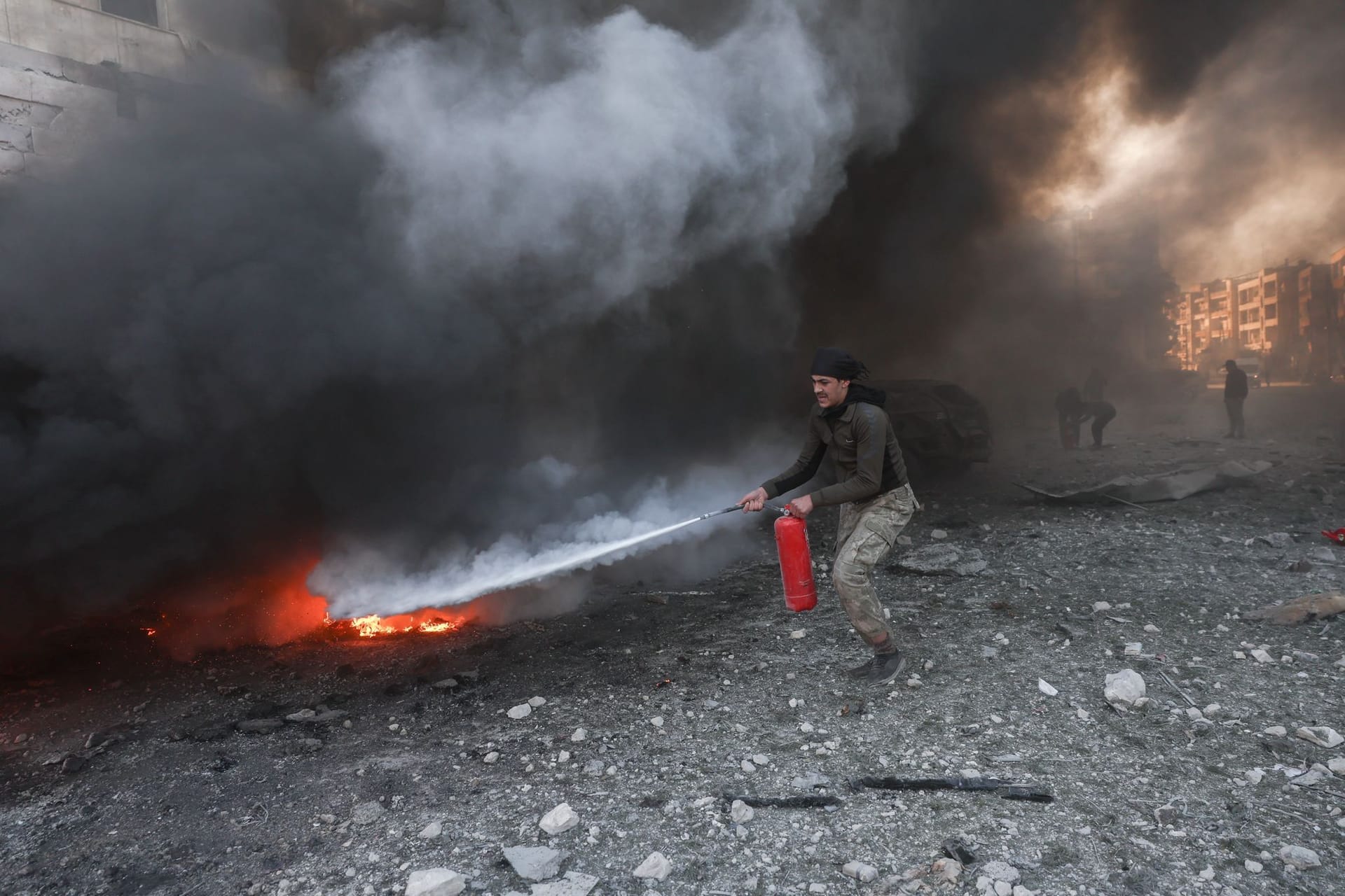 Ein Mann in Idlib versucht, das durch einen Luftangriff verursachte Feuer vor einem Krankenhauskomplex zu löschen. Ein Mann in Idlib versucht, das durch einen Luftangriff verursachte Feuer vor einem Krankenhauskomplex zu löschen.