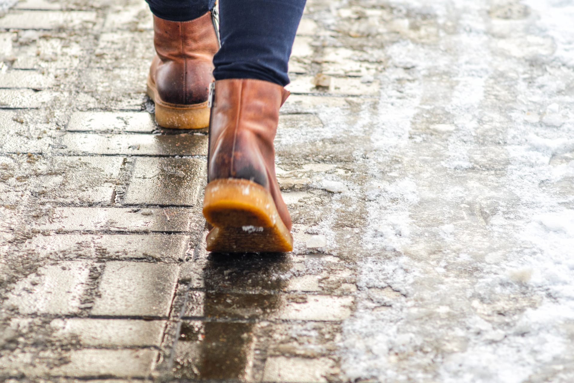 Jemand läuft mit Winterschuhen auf dem Bürgersteig: Kühlen die Zehen aus, weil die Schuhe durchfeuchtet sind, steigt das Risiko für Frostbeulen. Jemand läuft mit Winterschuhen auf dem Bürgersteig: Kühlen die Zehen aus, weil die Schuhe durchfeuchtet sind, steigt das Risiko für Frostbeulen.