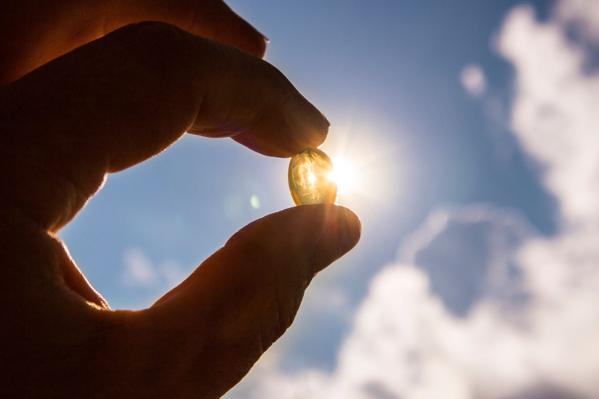 Jemand hält eine Vitamin-D-Kapsel zwischen den Fingern: Im Falle eines Mangels können Vitamin-D-Präparate ratsam sein.