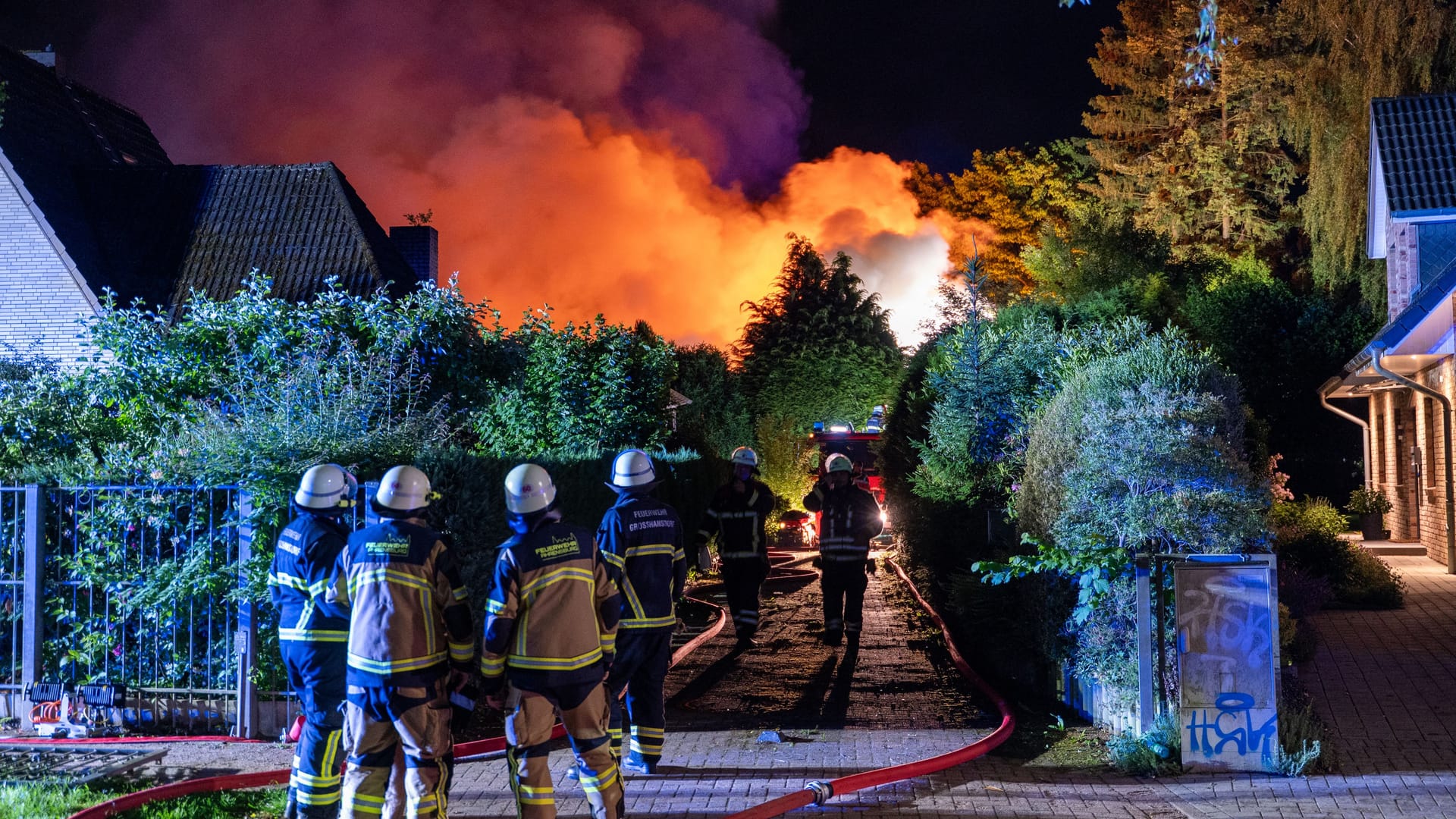 Feuerwehrleute stehen vor dem brennenden Haus: Der Feuerschein war weit am Nachthimmel in Großhansdorf zu sehen. Feuerwehrleute stehen vor dem brennenden Haus: Der Feuerschein war weit am Nachthimmel in Großhansdorf zu sehen.